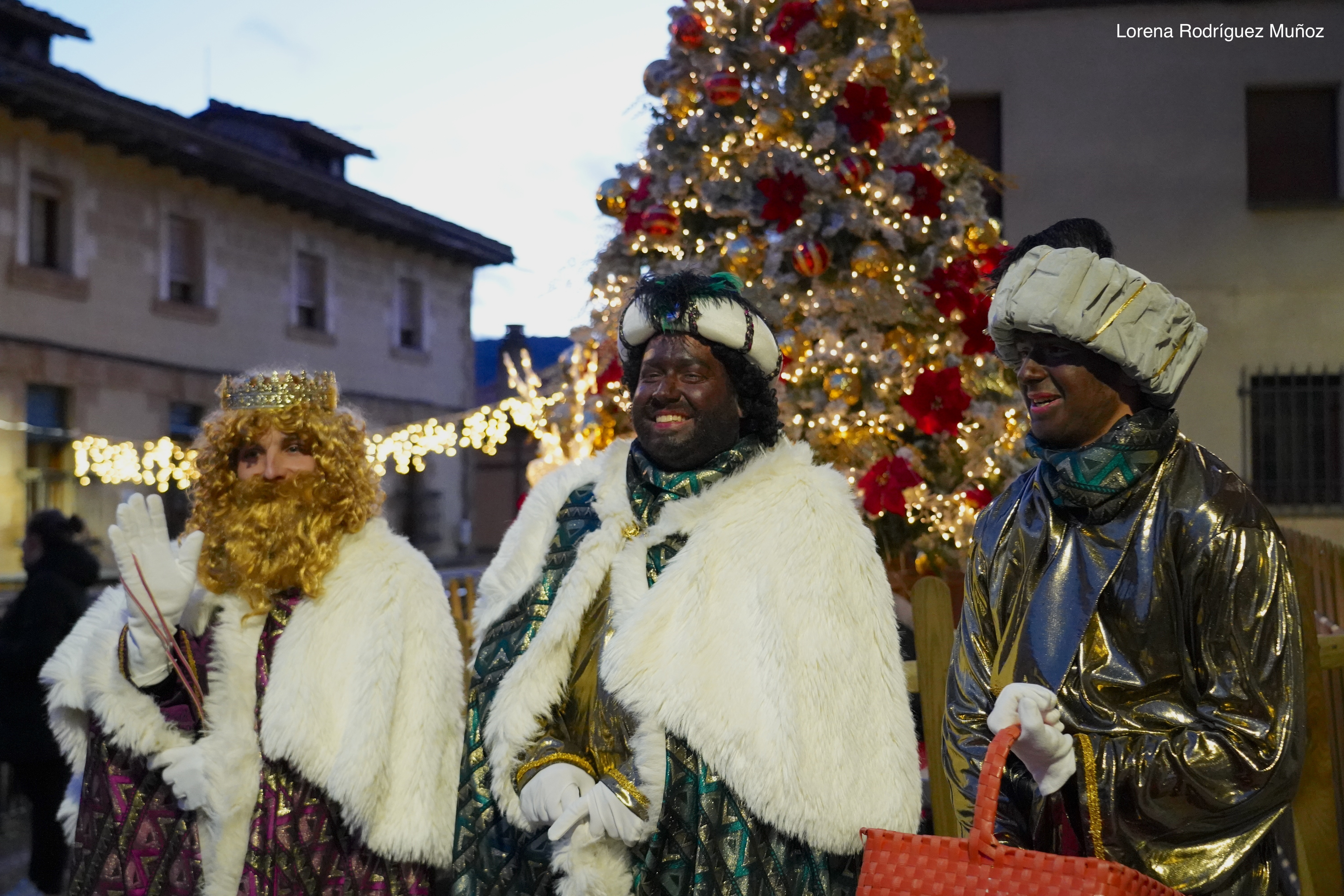 Fotografía de primer plano de los Reyes posando frente el árbol de navidad.